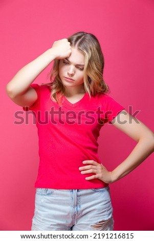 Beautiful Sad Depressed Caucasian Girl in Pink T-Shirt Posing in Summer Shorts With Lifted Hand Thinking Against Coral Pink Background. Vertical Image