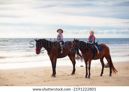 Kids riding horse on beach. Children ride horses. Cute blond kid in cowboy hat with USA flag on summer vacation on California or Florida coast. American boy on his pony on a ranch. Child and animal.