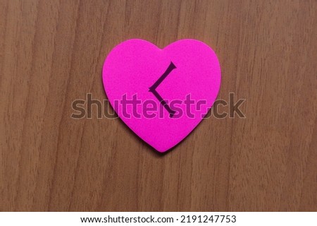 Shot of a pink paper heart, in which a rune is drawn above, in particular the rune is Kenaz