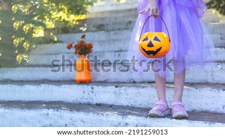 a girl holding a Jack-o-lantern in her hands. Children with a bucket of sweets in the autumn forest. Halloween celebration.