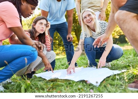 Group of friends with a map on the treasure hunt for cooperation and challenge Royalty-Free Stock Photo #2191267255