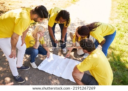 Young start-up team in nature on a treasure hunt with a map in a team building workshop Royalty-Free Stock Photo #2191267269