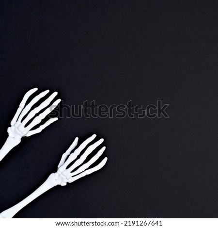 Scary skeleton hands on dark black background for Halloween with copy space. Flat lay minimal