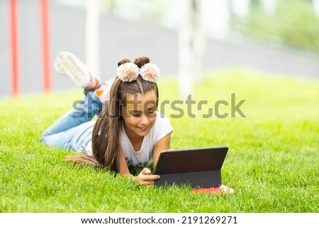 Positive caucasian little girl sitting with her digital tablet, chatting or have video call.