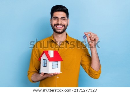 Photo of optimistic brunet young guy hold key home wear eyewear shirt isolated on blue color background
