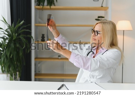Shot of female doctor holding an x-ray image and analyzing