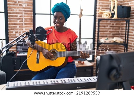 Young african american woman musician playing classical guitar at music Royalty-Free Stock Photo #2191289559