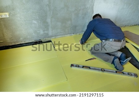 Installation of expanded polystyrene in the room for floor insulation, repair work alone, yellow expanded polystyrene, insulation of the house inside. Royalty-Free Stock Photo #2191297115