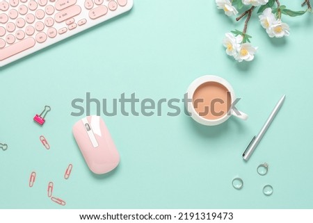 Top view office desk. Women's workspace of a blogger or freelancer. Keyboard, coffee cup and stationery on green pastel background. Spring stationery still life.