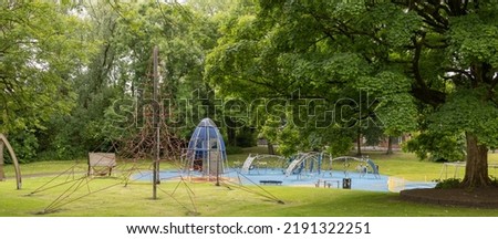 childrens play equipment in a local park, green trees and grass, no people