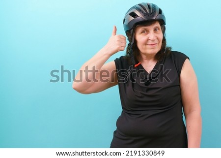 A happy woman wearing a bicycle helmet shows her thumb up on a blue background. Insurance. Injury. Protect. Secure. Protective. Perfect. Cycle. Express. Accident. Guard. Hobbies. Tool. Protector Royalty-Free Stock Photo #2191330849