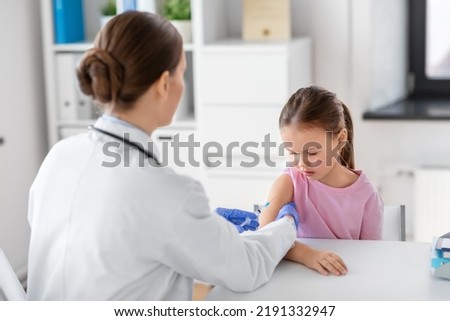 medicine, healthcare and vaccination concept - female doctor or pediatrician with syringe making vaccine injection to little girl patient at clinic Royalty-Free Stock Photo #2191332947