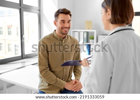 medicine, healthcare and people concept - female doctor showing clipboard to smiling man patient at hospital Royalty-Free Stock Photo #2191333059