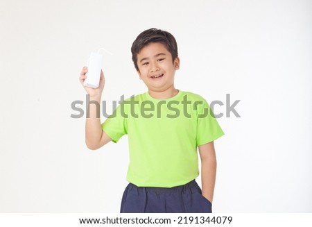 Portrait of a little young handsome kid boy in green shirt, hold drinking milk box mockup, isolated on white background. Concept of happy good nutrition