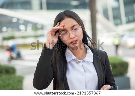 A corporate employee gently massages her forehead as she is having a headache due to stress from her work. A young lady has a headache due to uncorrected eyesight or the wrong eyeglass lens.