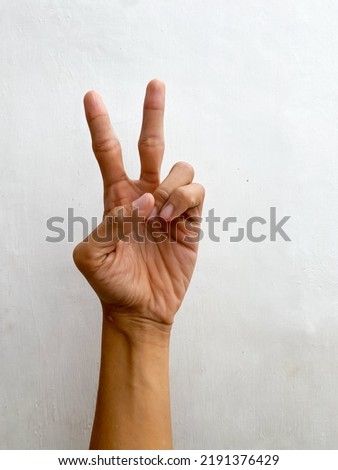 Male hand showing 2 fingers or Victory gesture, isolated on white background. Hand of man with empty space. Hand doing gesture of number Two.