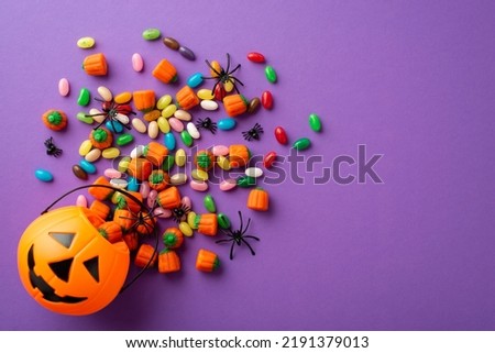 Top view photo of halloween decorations pumpkin basket with candies and spiders on isolated violet background Royalty-Free Stock Photo #2191379013
