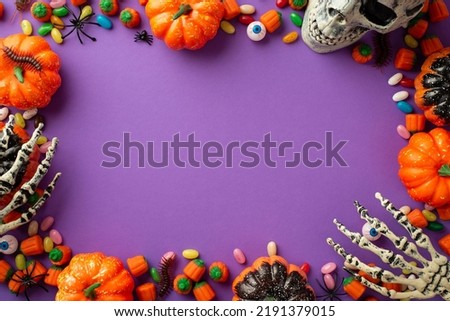 Halloween concept. Top view photo of pumpkins skull skeleton hands candies eyes spiders and centipedes on isolated violet background with copyspace in the middle