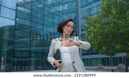 Calm businesswoman looking time on hand watch while going to the work after break Royalty-Free Stock Photo #2191380999