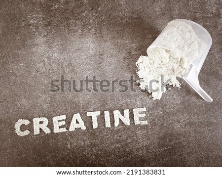 Creatine powder text font on grey stone background with plastic spoon cup. Creatine supplement for sporting performance enhancement Royalty-Free Stock Photo #2191383831