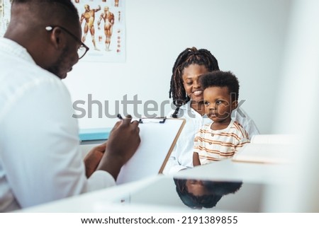 Smiling young African American mother with small 2s boy child son have consultation with caring male pediatrician in private hospital or clinic. Attentive male doctor support cheer little kid patient.
