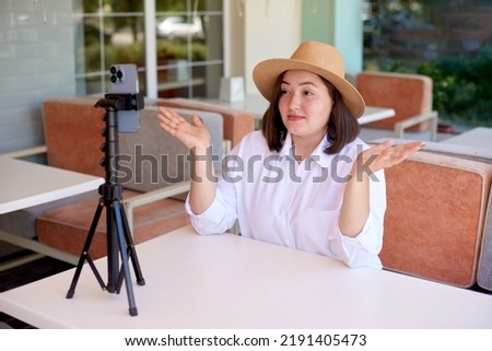 woman in white shirt show shrug gesture in mobile phone working or study online do live streaming. shallow depth of field