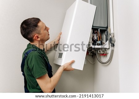 Plumber attaches Trying To Fix the Problem with the Residential Heating Equipment. Repair of a gas boiler Royalty-Free Stock Photo #2191413017