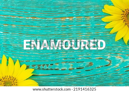 ENAMOURED - text, yellow flowers, sunflowers, wooden background (copy space).