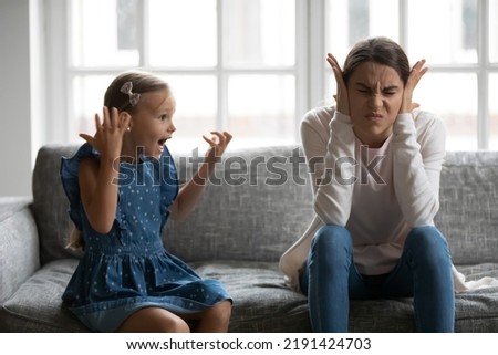 Close up upset mother covering ears, having problem with noisy naughty daughter yelling, screaming, demanding attention, frustrated mum tired of difficult child, tantrum manipulation concept Royalty-Free Stock Photo #2191424703
