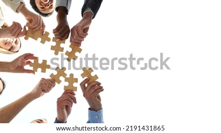 Blank creative text copyspace background with diverse team of business people putting pieces of jigsaw puzzle together, low angle, shot from below, bottom view. Teamwork and cooperation concept Royalty-Free Stock Photo #2191431865