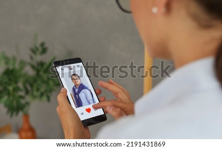 Single woman uses smartphone to find love. Woman using dating app on mobile phone and swiping user photos and pressing red button. Close up of smartphone with open profile of man. Selective focus.