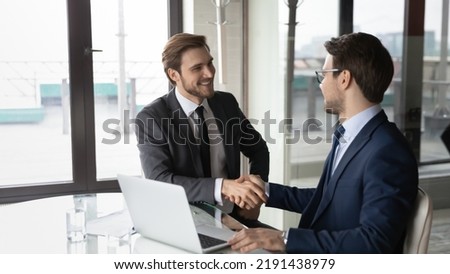 Wide banner view of smiling businessmen shake hands close deal make agreement after successful negotiations in office. Happy male business partners handshake get acquainted greeting at meeting.