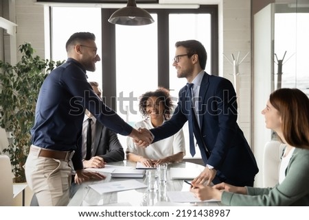 Smiling multiethnic businesspeople shake hands close deal make agreement after successful company meeting in office. Happy international businessmen handshake get acquainted greeting at briefing.