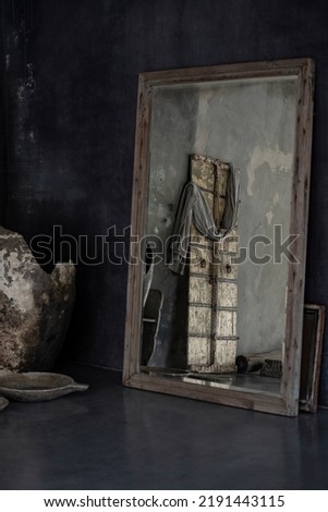 Photo of rustic concrete designer interior with old wooden door, big mirror, artistic vase and bowls. Natural sunlight. Decoration. Inspiration.