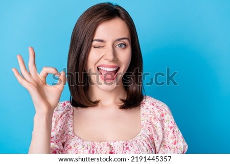 Closeup photo of young attractive pretty nice girl showing okey sign blink eye everything okey work done hint isolated on blue color background Royalty-Free Stock Photo #2191445357