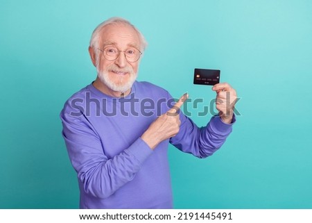 Photo of cheerful nice granddad indicate finger hold demonstrate debit card isolated on turquoise color background