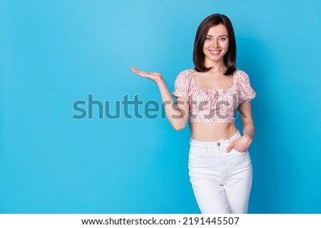 Portrait photo of young pretty cute nice girl wear stylish blouse hold hand demonstrating new app dating isolated on blue color background