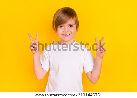 Portrait of handsome cheerful pre-teen boy showing double v-sign good mood isolated over bright yellow color background