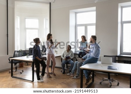 Multiethnic work group talk at meeting, discuss business ideas, sharing creative thoughts. Diverse colleagues office employees speaking negotiating at informal briefing at modern co-working Royalty-Free Stock Photo #2191449513