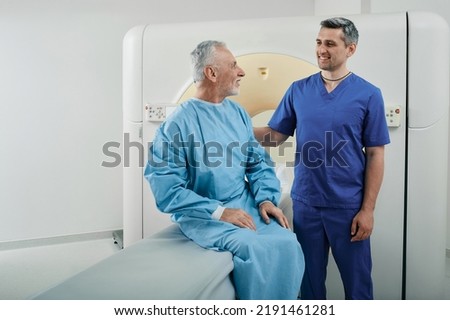 Radiographer talking with male patient in hospital radiology department prior to CT scan being performed. Computed Tomography Royalty-Free Stock Photo #2191461281