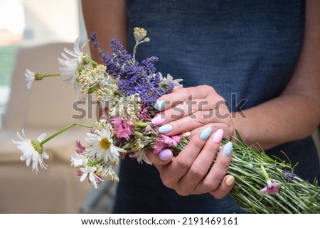 a young woman with a beautiful summer manicure holds a bouquet of wild flowers