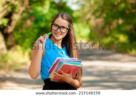 Teen girl with books in hands near tree