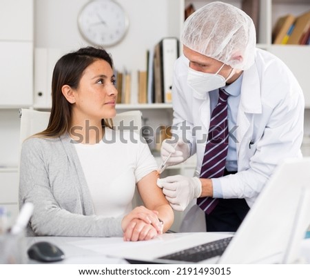 Doctor giving Covid-19 or flu antivirus vaccine shot to patient wear face mask protection at medical office Royalty-Free Stock Photo #2191493015