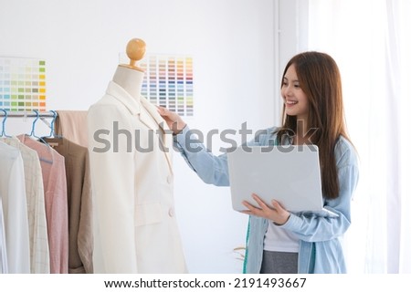 Fashion designer working in studio, cutting drawing, sewing dress