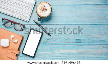 Top view, Office desk with computer keyboard, eyeglass, Blank screen smart phone, pen, notebook and cup of coffee, copy space, Mock up.	

