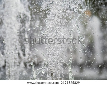 Water splashes from fountain on dark background. Natural texture of only water of fountain. High waves effect in hot summer with copy space. Water sprays in sunny day close-up. Royalty-Free Stock Photo #2191525829