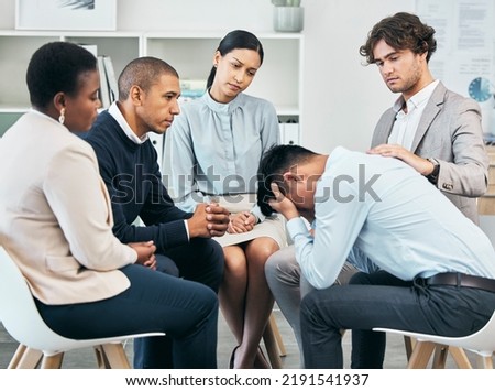 Depression, support and unity by colleagues comforting male after getting bad news at work. Community care from workers sitting together, supporting their friend after being fired or through grief Royalty-Free Stock Photo #2191541937