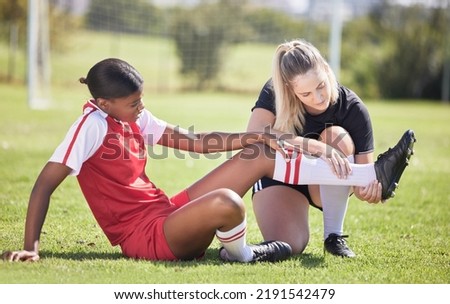 Soccer, sports and injury of a female player suffering with sore leg, foot or ankle on the field. Painful, hurt and discomfort woman getting her pain checked out by athletic trainer on the pitch. Royalty-Free Stock Photo #2191542479