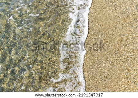 A pattern of waves crashes onto a rocky beach. View from above. Background,