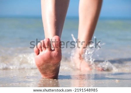 woman walking to sea and beach on a beautiful island Ocean foam wrapped around a girl's leg. Her legs touched the splashing water. Hit the skin on the legs and she walked in the soft sunshine morning